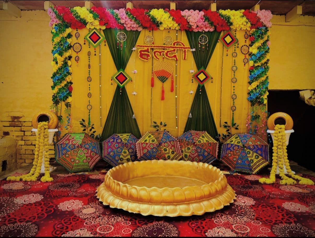 Haldi ceremony backdrop with multicolour florals and decorative umbrellas