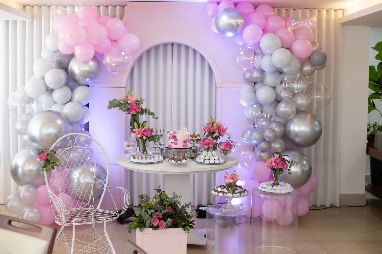 Celebration setup at home with a balloon arch, florals and dessert table