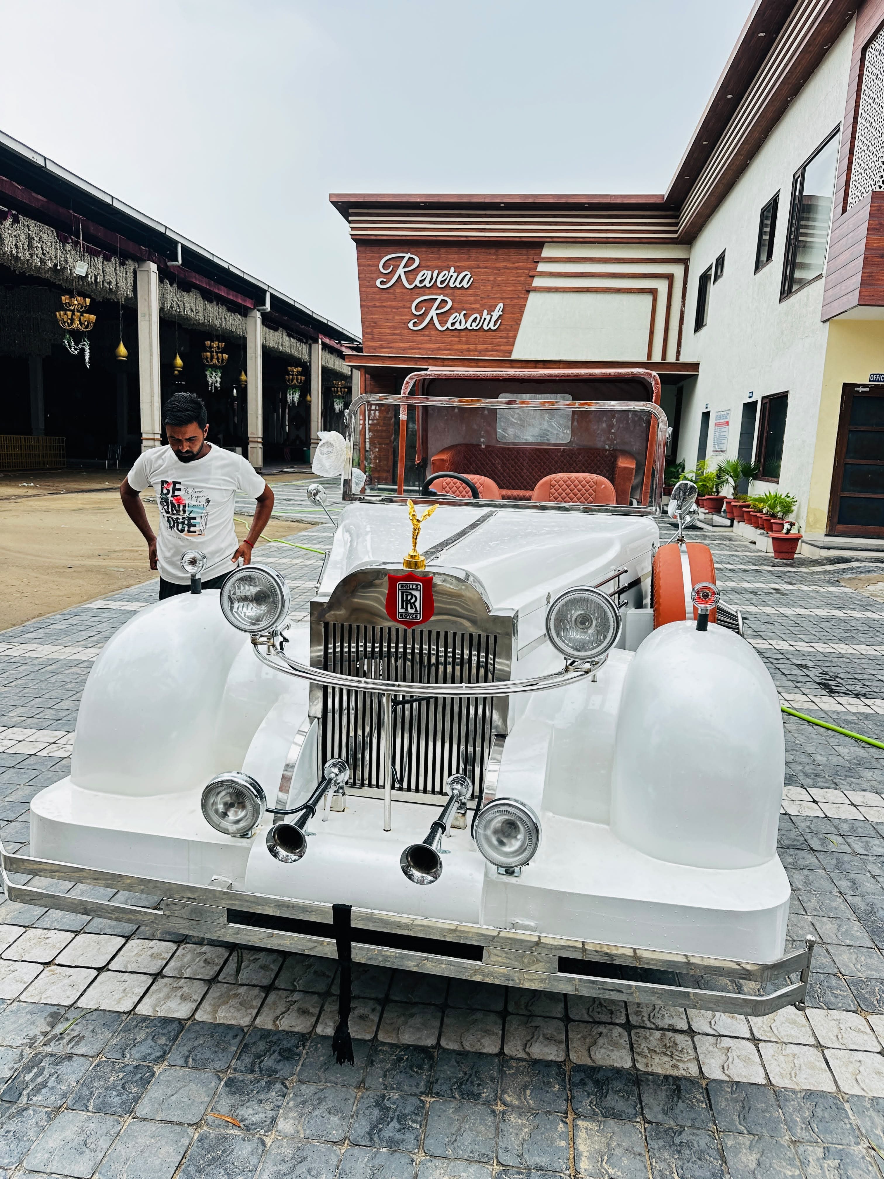 White vintage convertible wedding car parked at a resort entrance
